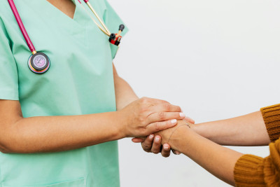 Arzt hält fürsorglich Hände von Patienten nach Feigwarzen-Behandlung
